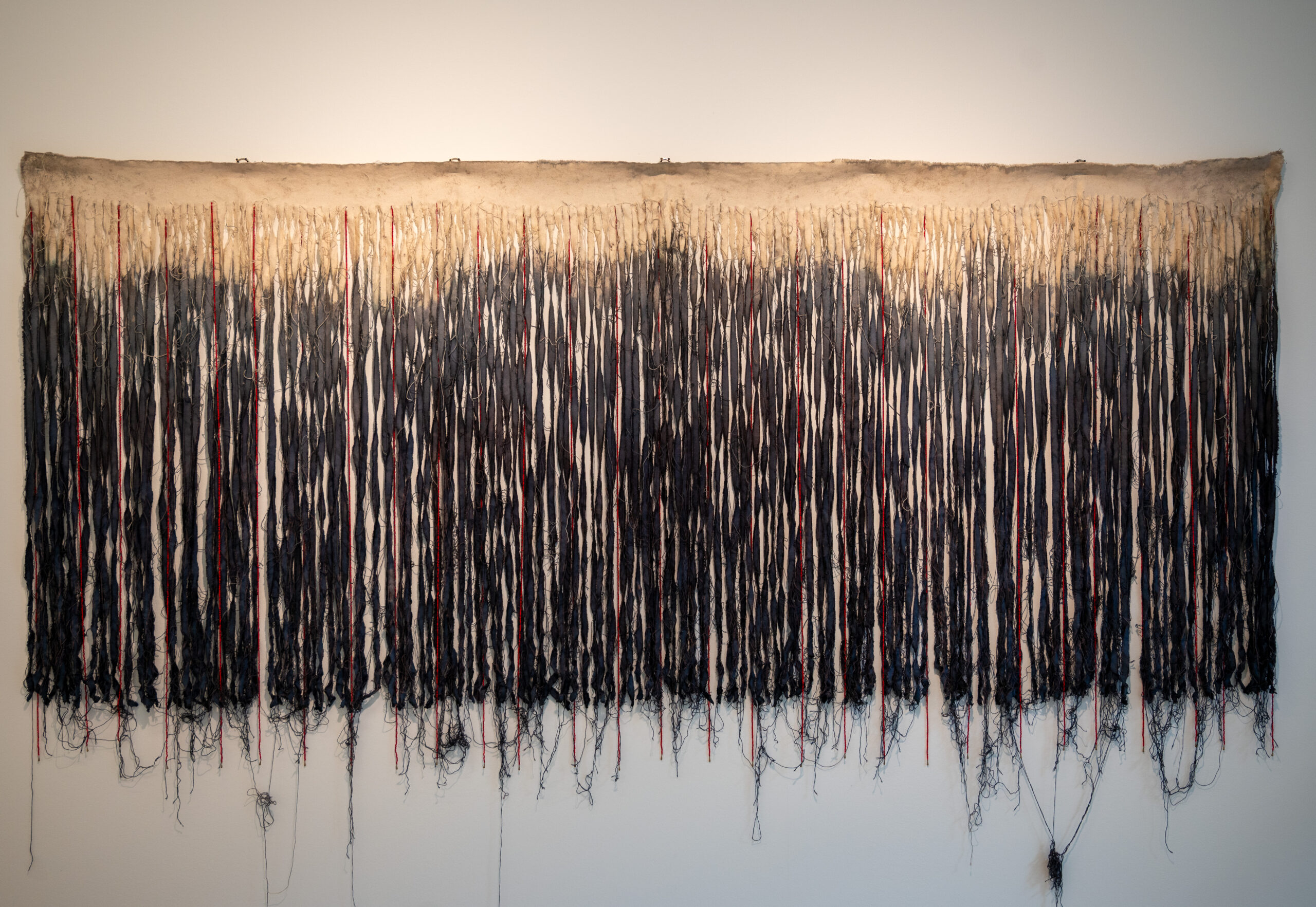 Seven-foot by three-foot piece of canvas, split into two colors tan and black, and a frayed fringe.