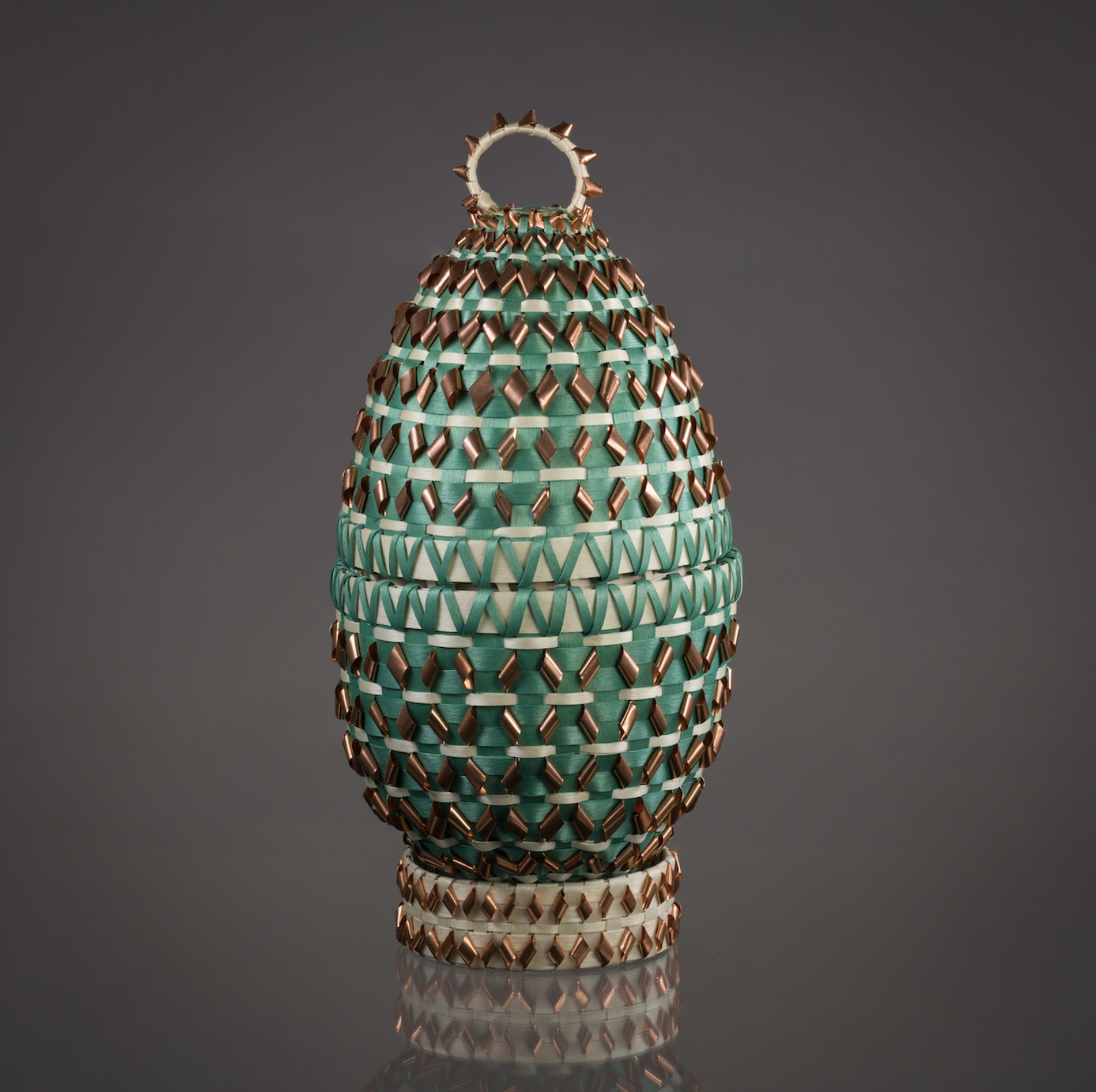 An egg shaped basket woven with green and copper material