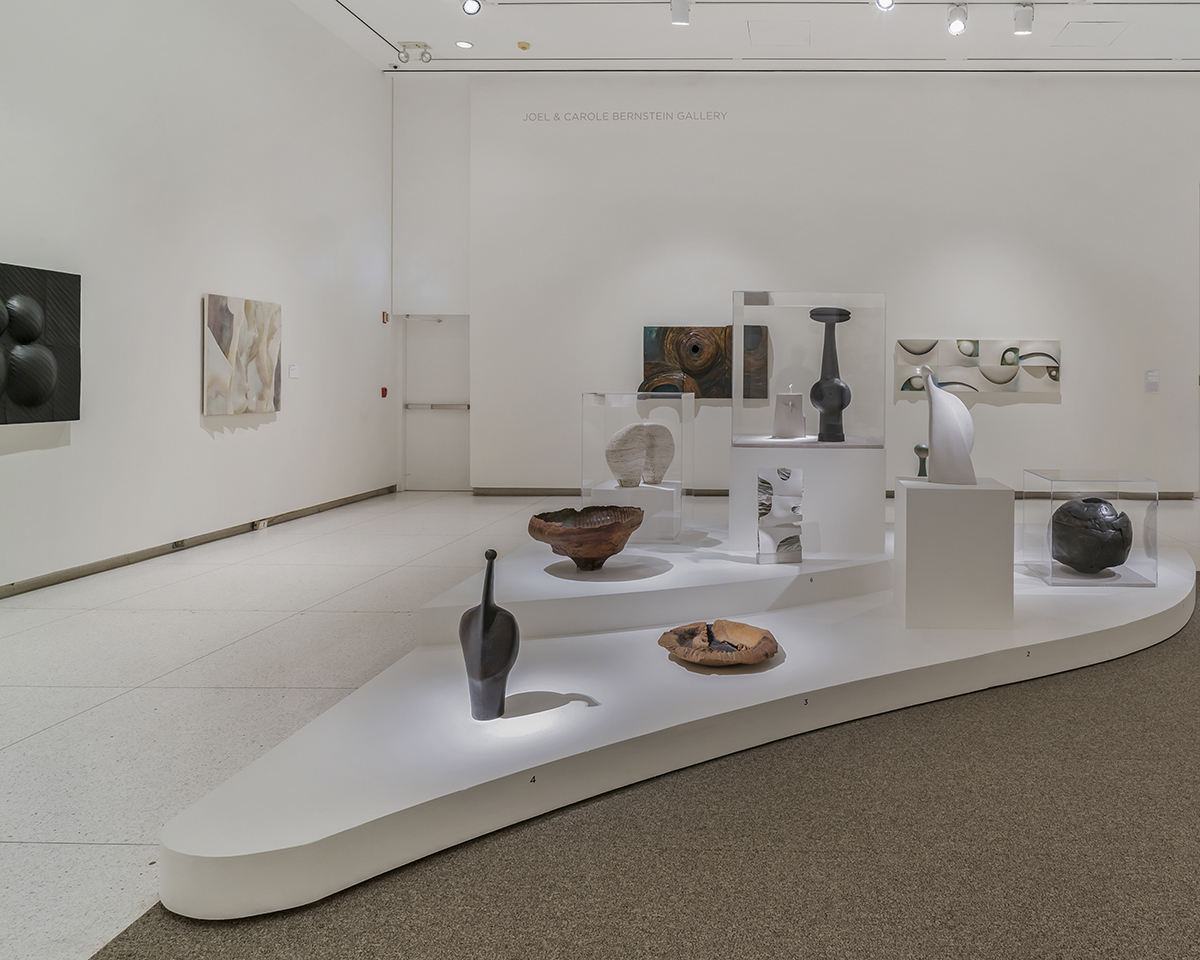 An installation of ceramic sculptures on a curved plinth.