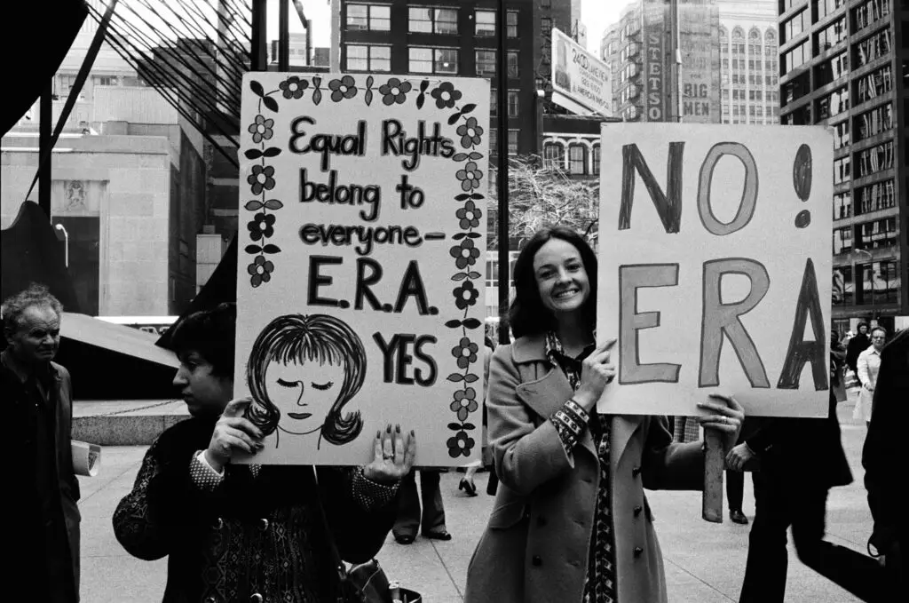 Two women hold up signs that say "Equal Rights for Everyone -- ERA Yes" and "NO! ERA."