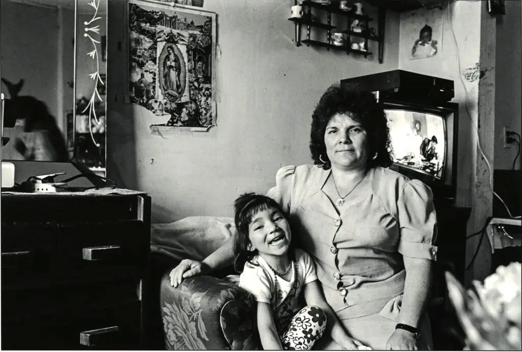 Portrait of a mother and child seated in a living room space with a television over the mother's left shoulder.