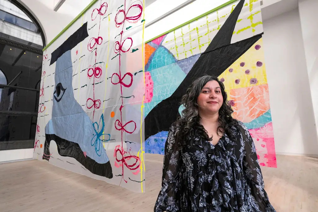 Artist Victoria Martinez stands in front of an installation of her large-scale textile artworks.