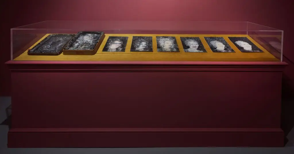A gallery case holds a series of eight portraits of women.