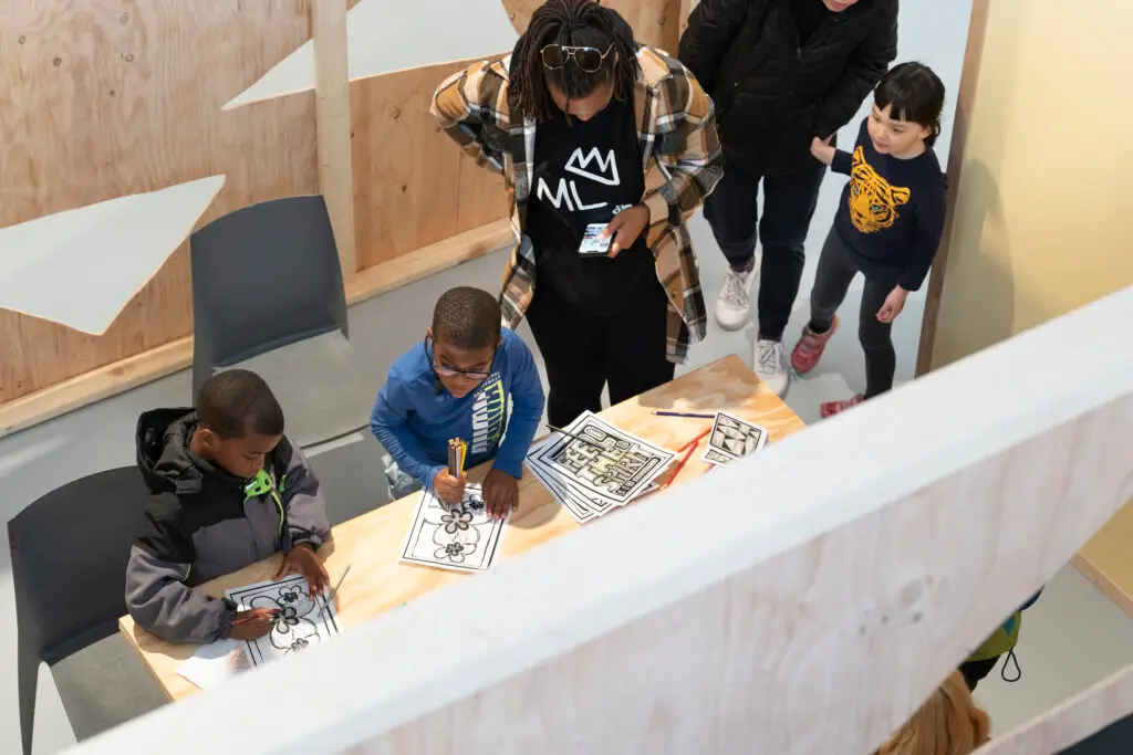 A bird's eye view of children and parents at a table working on a craft project.