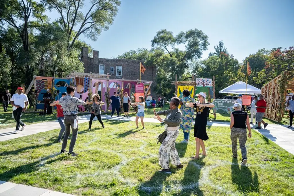 A group of eight people assembled in a park space and doing a movement exercise together.