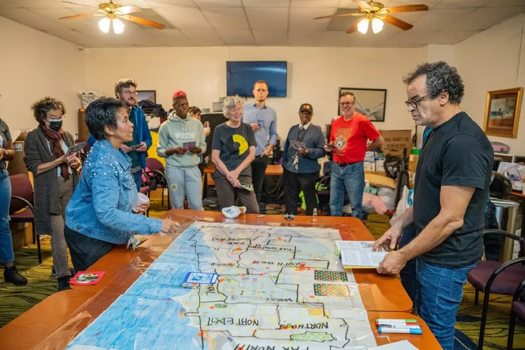 A group stands around a table with a large map set on top.