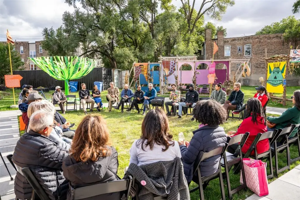 A large is outside seated in chairs in a circle.