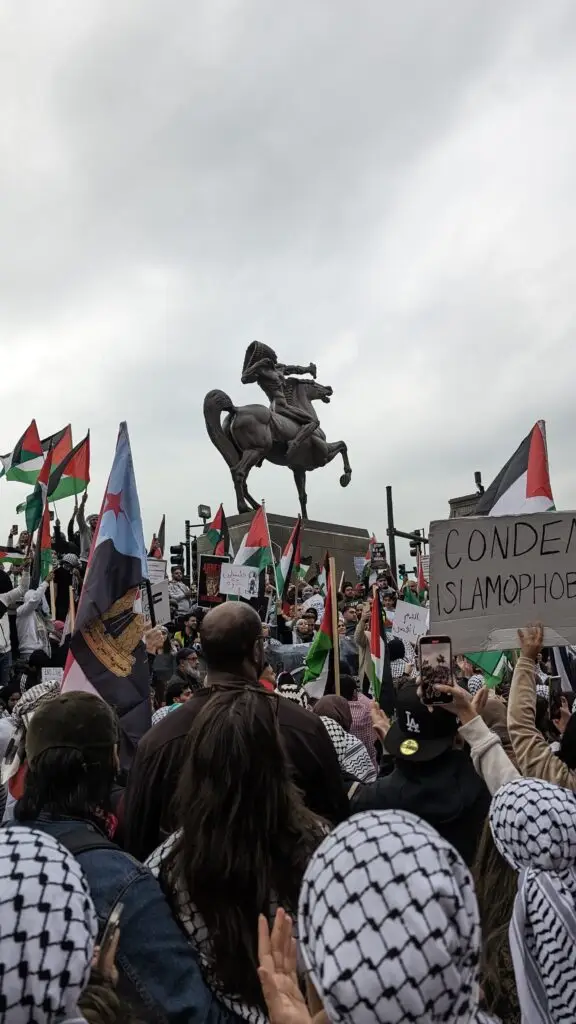 Protestors gather at the Congress Plaza around The Bowman, a sculpture of a Native figure on horseback.