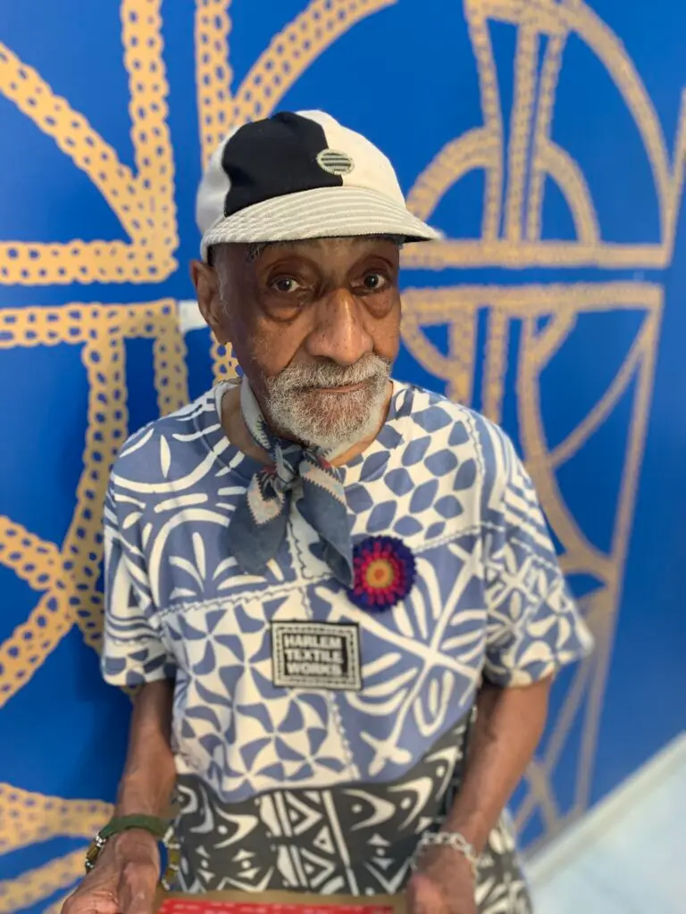 Portrait of Robert Paige wearing a hat, scarf, and patterned shirt.