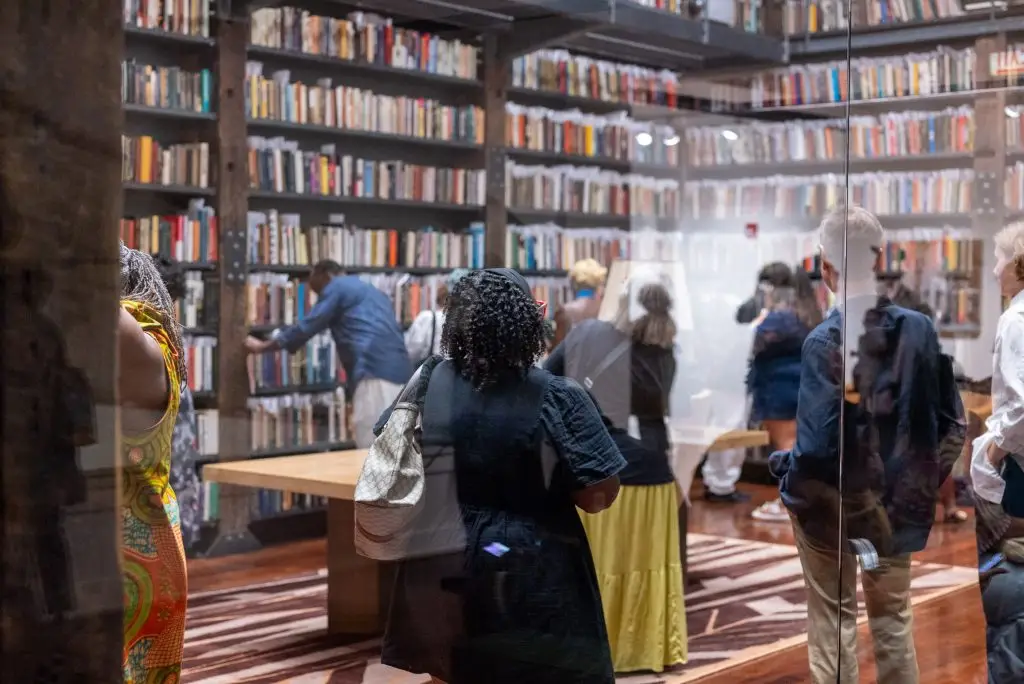 Visitors standing and interacting in front of stacks of full bookshelves.